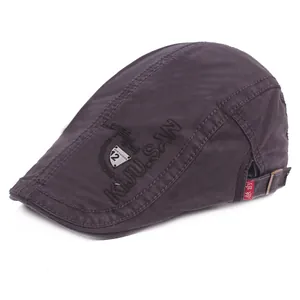 Close-up of brown flat cap showing embroidery and adjustable metal buckle strap