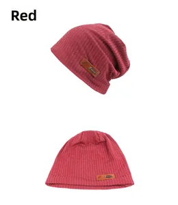 Macro detail of red knitted beanie featuring vertical stripes and a brown leather label