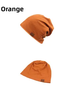 Detail of orange knitted beanie featuring a brown leather patch with F&S embossed letters