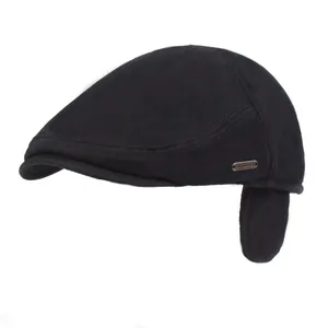 Men's winter black beret cap with ear flaps and metal logo detail on white background