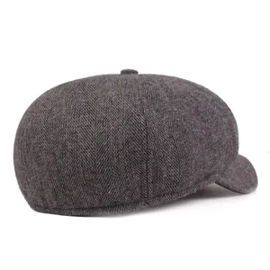 Detail of grey herringbone newsboy cap featuring wool texture and decorative top button