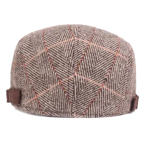 Men's brown herringbone newsboy cap with orange plaid pattern and side strap detail