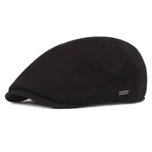 Detailed close-up of a black winter beret hat with a metallic logo plate and neat stitching