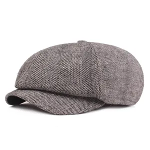 Detail of grey newsboy cap showing grey herringbone fabric and classic octagonal design