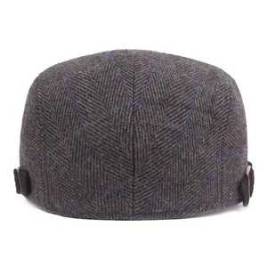 Detail of dark grey herringbone tweed ivy cap with blue plaid and black side buckles