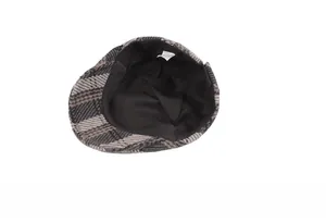 Detailed view of the black fabric lining and care label inside the plaid wool beret hat