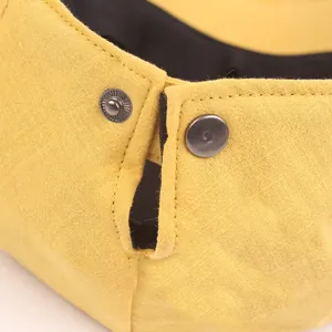 Detailed macro view of yellow beret hat fabric with dark metal snap button and stitching