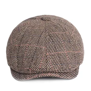 Close-up of brown newsboy cap with herringbone pattern and orange windowpane check texture