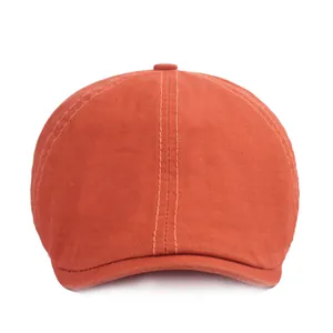Détail d'une casquette plate orange montrant la texture du tissu et les coutures de qualité
