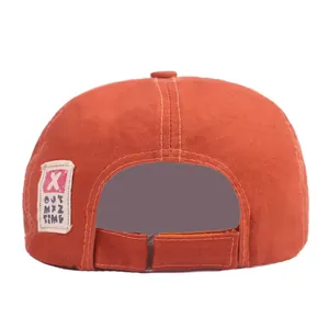 Détail du béret en coton orange avec sangle réglable et écusson de logo brodé
