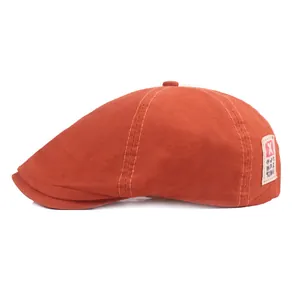 Détail d'un béret orange en coton avec étiquette vintage et coutures fines sur fond blanc