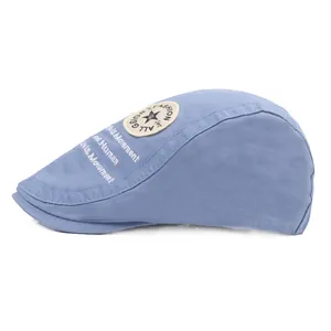 Détail du béret bleu clair avec écusson étoile vintage et texte brodé sur le côté
