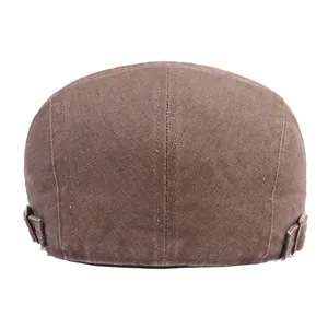 Detail view of the brown denim flat cap featuring adjustable bronze metal buckles at the back