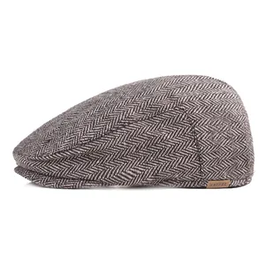 Close-up of herringbone tweed pattern and leather logo detail on grey flat cap