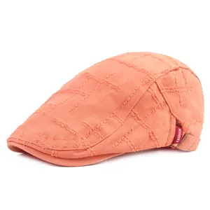 Détail du béret orange délavé avec motif quadrillé et étiquette fashion rouge latérale