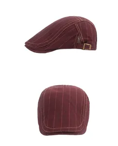 Détail de la casquette rayée bordeaux avec boucle en métal et surpiqûres jaunes