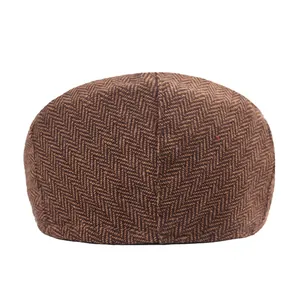 Close-up of brown herringbone tweed newsboy cap showing wool fabric texture and stitching