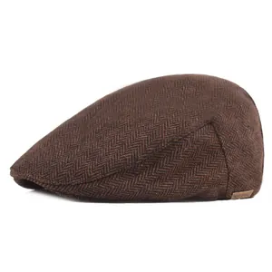 Detailed view of brown herringbone wool flat cap with vintage texture and leather side label