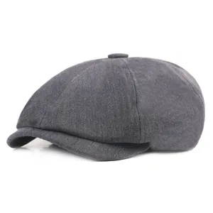 Détail macro du tissu à chevrons gris foncé et du bouton de cette casquette gavroche