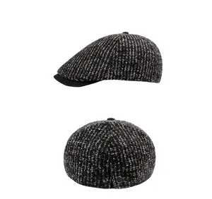 Détail de la casquette plate en tricot gris avec visière noire et boutons argentés