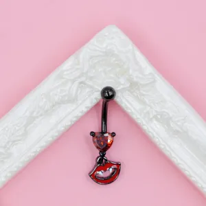 Detail of bat-themed gothic belly ring with red heart zircon and vampire lip pendant
