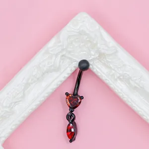 Macro shot of gothic black belly ring with heart-shaped red gems on a white frame