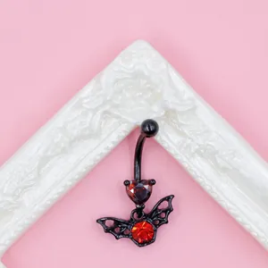 Gothic bat belly piercing with red heart zircon and black surgical steel on pink background