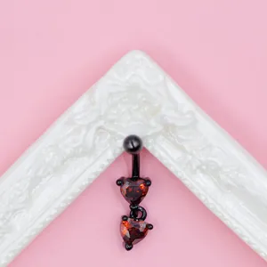 Macro detail of gothic black bat belly ring with red heart zircon and metal bar