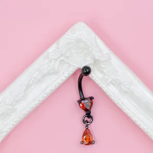 Close-up of black curved barbell with two red heart-shaped zircon stones for piercing