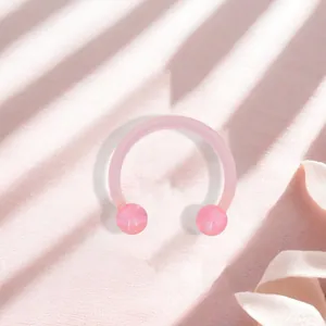 Macro detail of pink acrylic horseshoe nose ring with marble effect beads on soft fabric
