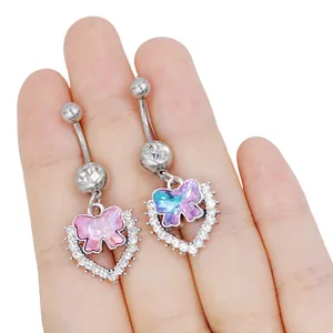 Primer plano de piercing de ombligo plateado con colgante de corazón y cristal mariposa