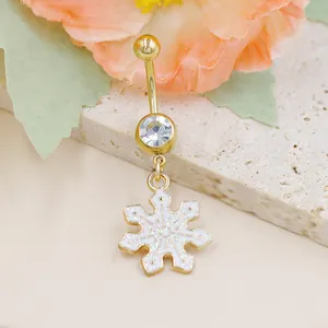 Primer plano del piercing de ombligo dorado con copo de nieve brillante y cristal
