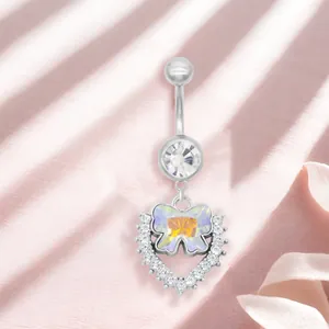 Piercing de ombligo plateado con mariposa y colgante de corazón sobre satén rosa