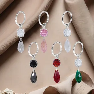 Surgical steel hoop earrings with colorful zircon droplets on beige silk background