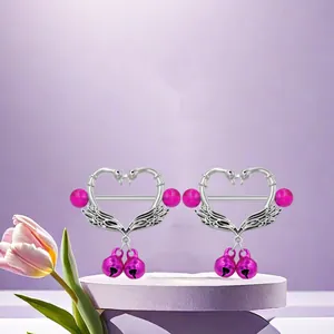 Detail view of heart-shaped swan nipple rings with pink bells on purple base