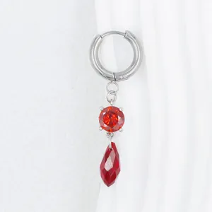 Detalle de pendiente plateado con cristales rojos facetados redondos y en forma de gota