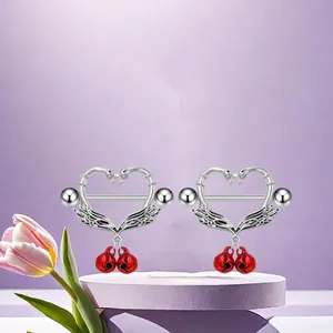 Detail of silver nipple rings with swan heart frame and small red bells on purple stand