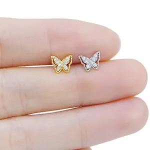 Macro shot of tiny butterfly stud earrings with sparkling cubic zirconia on fingertips