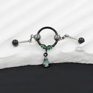 Detail of gothic stainless steel bat earring bridge with green gemstone pendant on stone