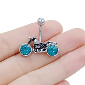 Detailed close-up of motorcycle belly button ring with teal crystals held by fingers