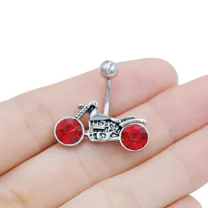Detailed macro view of motorcycle navel ring with red gemstones held in hand