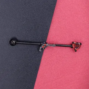 Industrial barbell detail with black gun charm and red heart-shaped gemstone