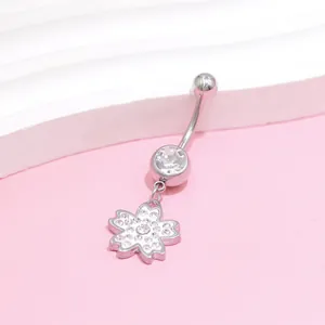 Macro view of stainless steel belly ring with zircon flower pendant on pink background