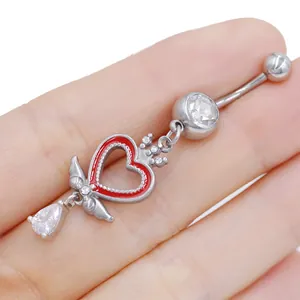 Dettaglio piercing ombelico a cuore rosso con ali d'argento e gocce di cristallo