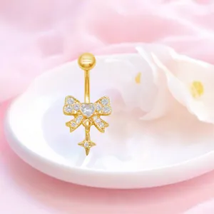 Makroansicht des goldenen Schleifen-Bauchpiercings mit Herzzirkon und Sternanhänger
