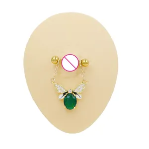 Macro view of gold bee nipple ring with green zircon and white crystals on silicone model