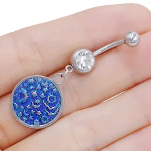 Dettaglio di un piercing all'ombelico in acciaio con ciondolo celeste blu e stelle