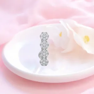 Detailansicht silberner Bauchnabelpiercing mit Kristallclustern auf weißer Keramik