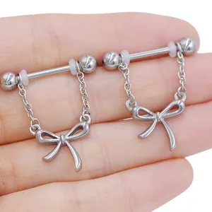Detail of silver bow pendant nipple rings with dangling chains shown on hand