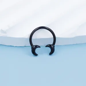 Close-up of black gothic horseshoe septum ring with crescent moon ends on a textured stone
